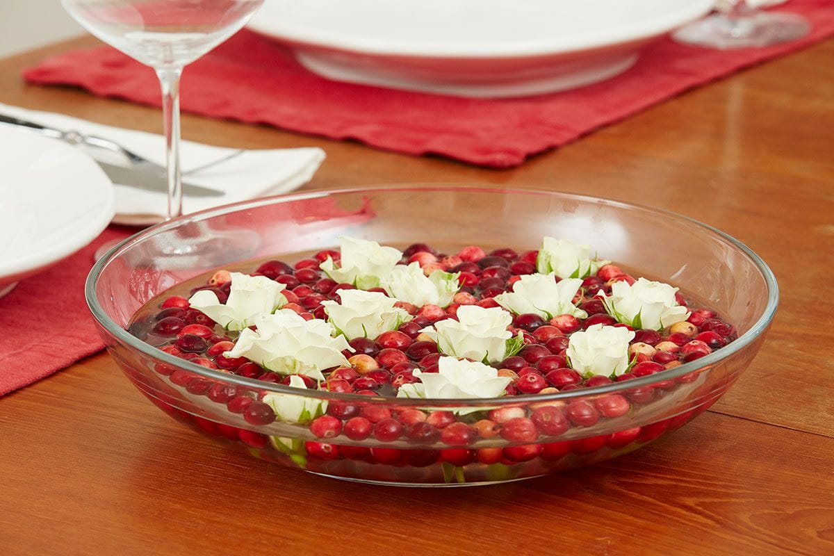 cranberries and white flowers floating in water in bowl