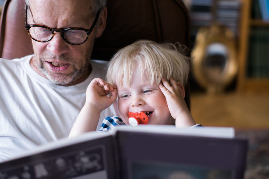 Grandfather reading book to happy grandson