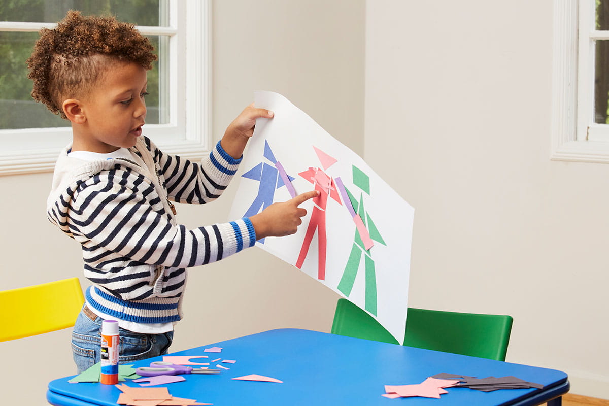 Young boy holding up his Picasso-inspired art.