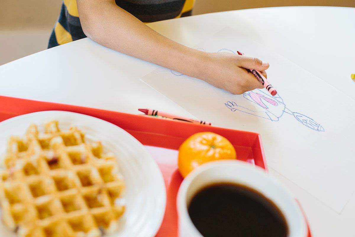child coloring near waffles