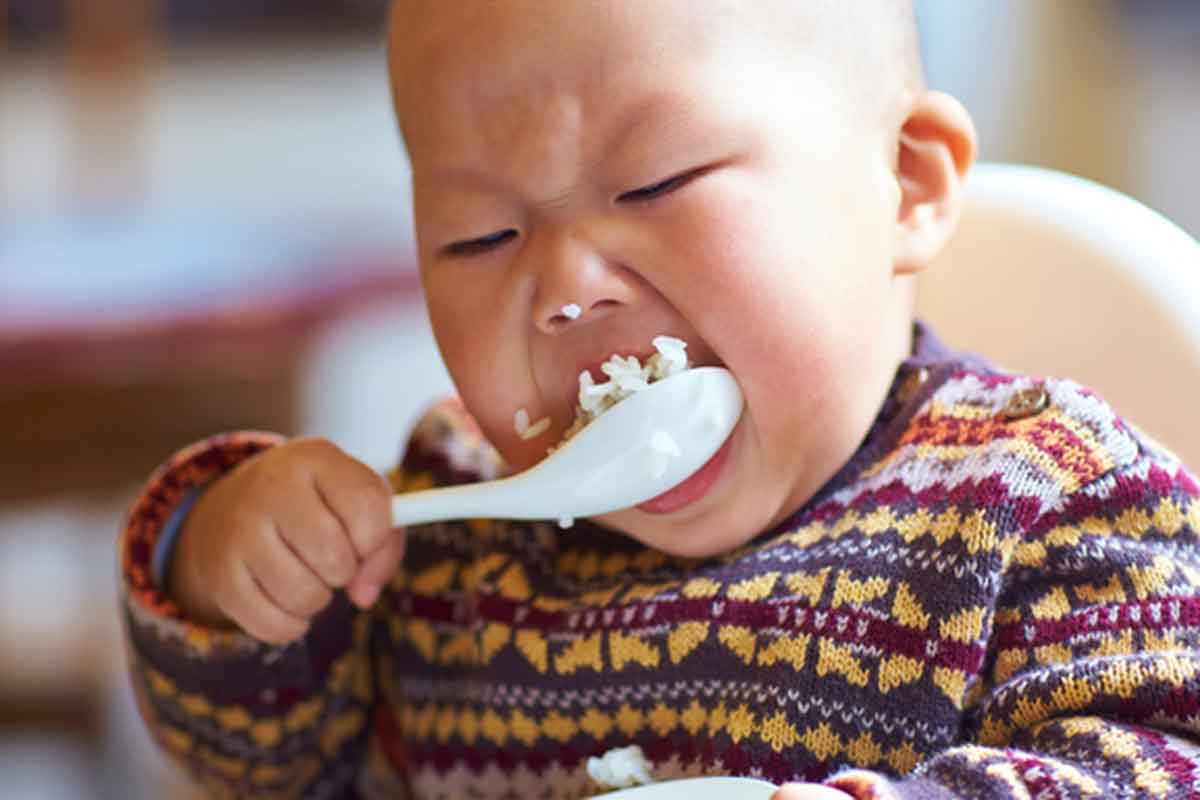 Asian boy eating rice out of a spoon