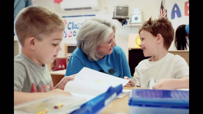 Daycare teacher at KinderCare helping young children