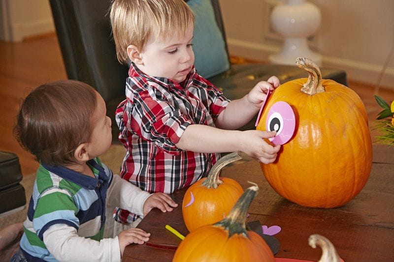 two boys putting pumpkin head together