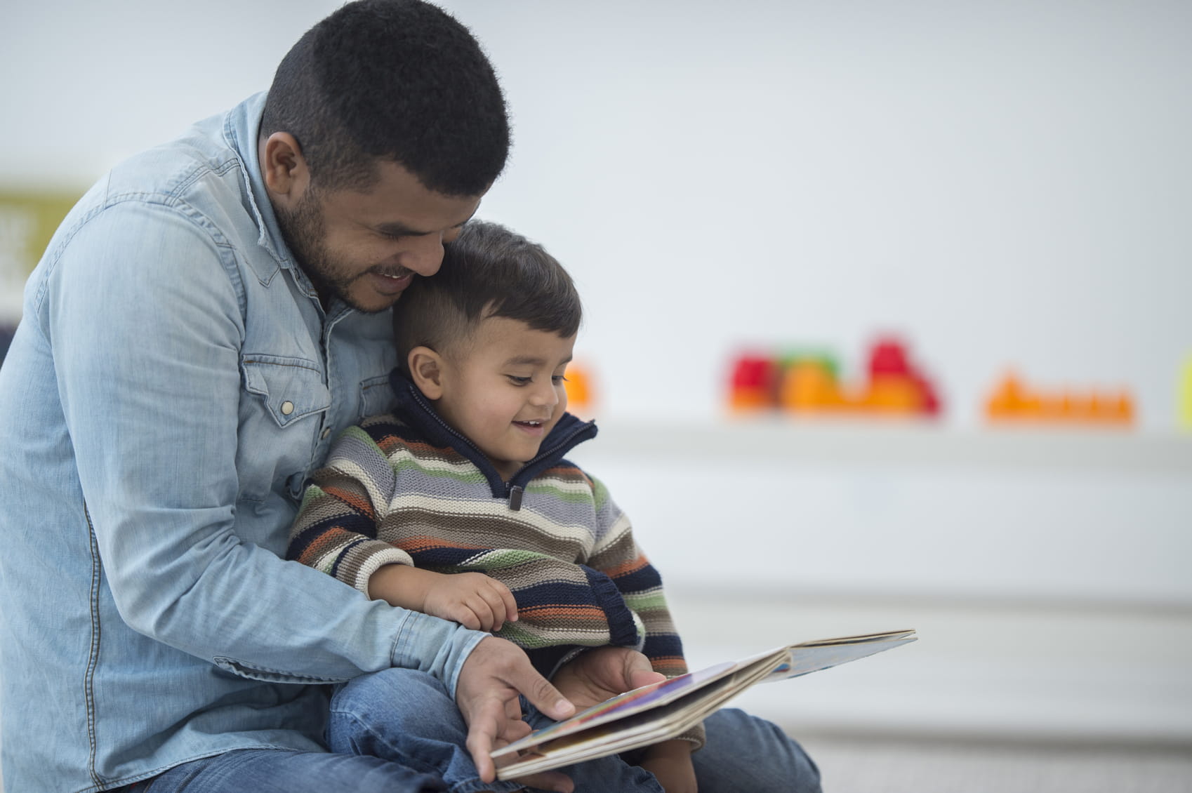 Dad and toddler son reading book