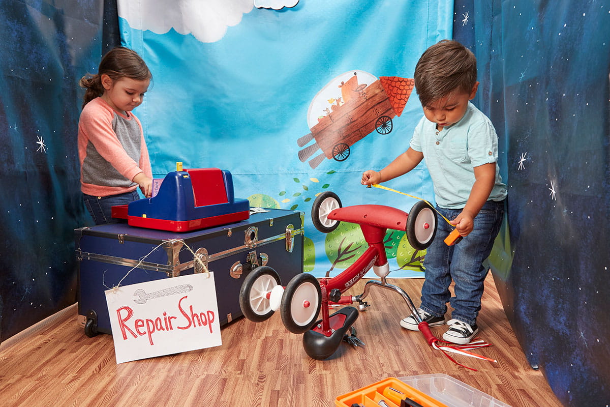 Girl and boy pretending to play tricycle repair shop