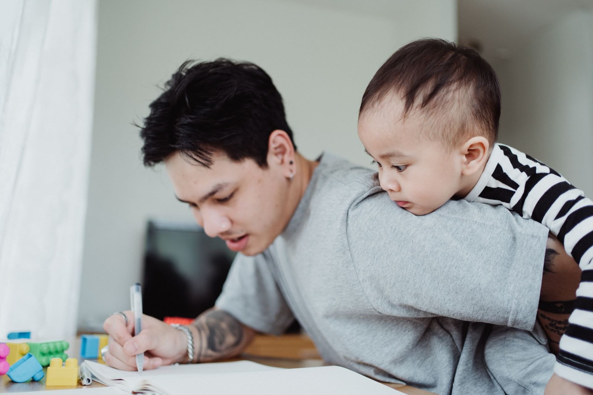 A father multitasking work while carrying his child