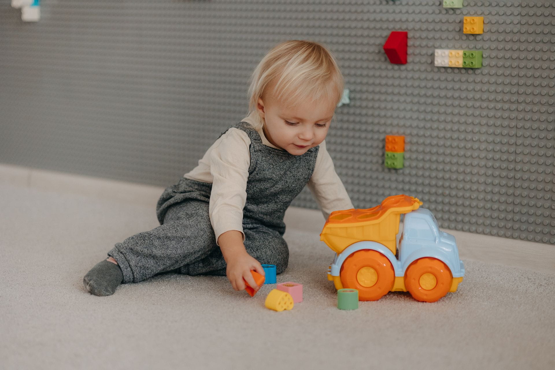 Cute toddler engaged with colorful blocks and toy truck indoors