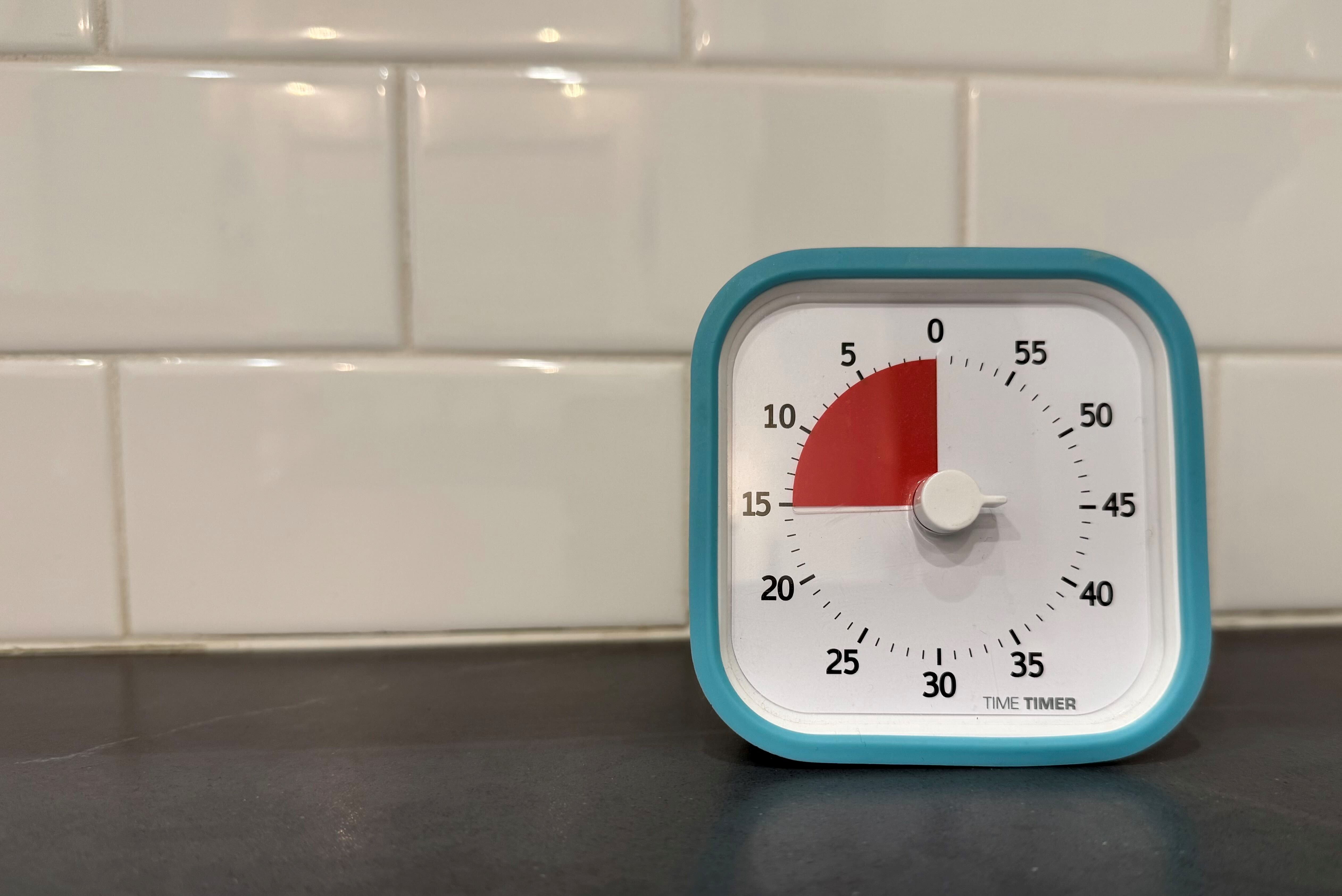 A close-up of a classic analog kitchen timer on a counter