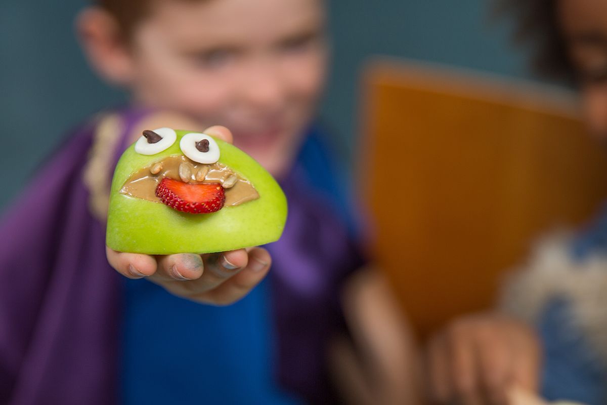 child holding up monster apple mouth