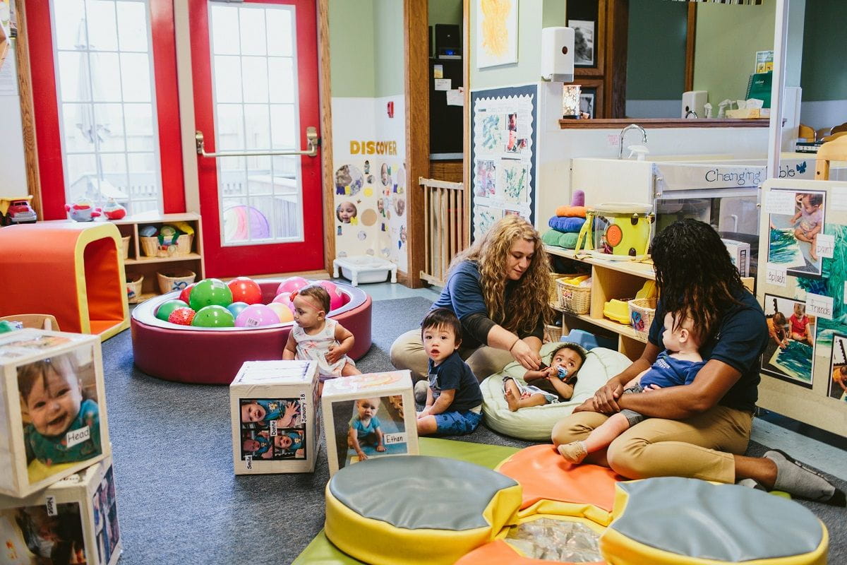 Regina and fellow teacher on floor with babies