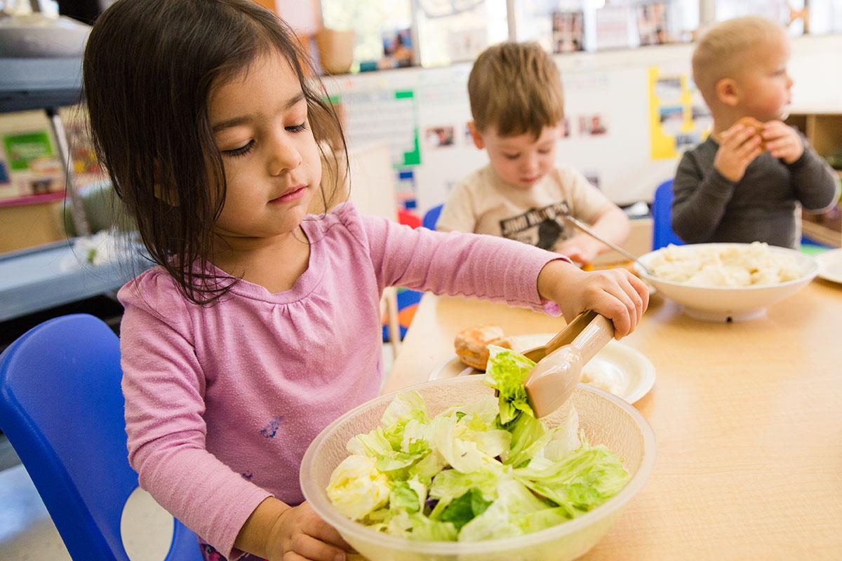 little girl helping herself to salad feature image