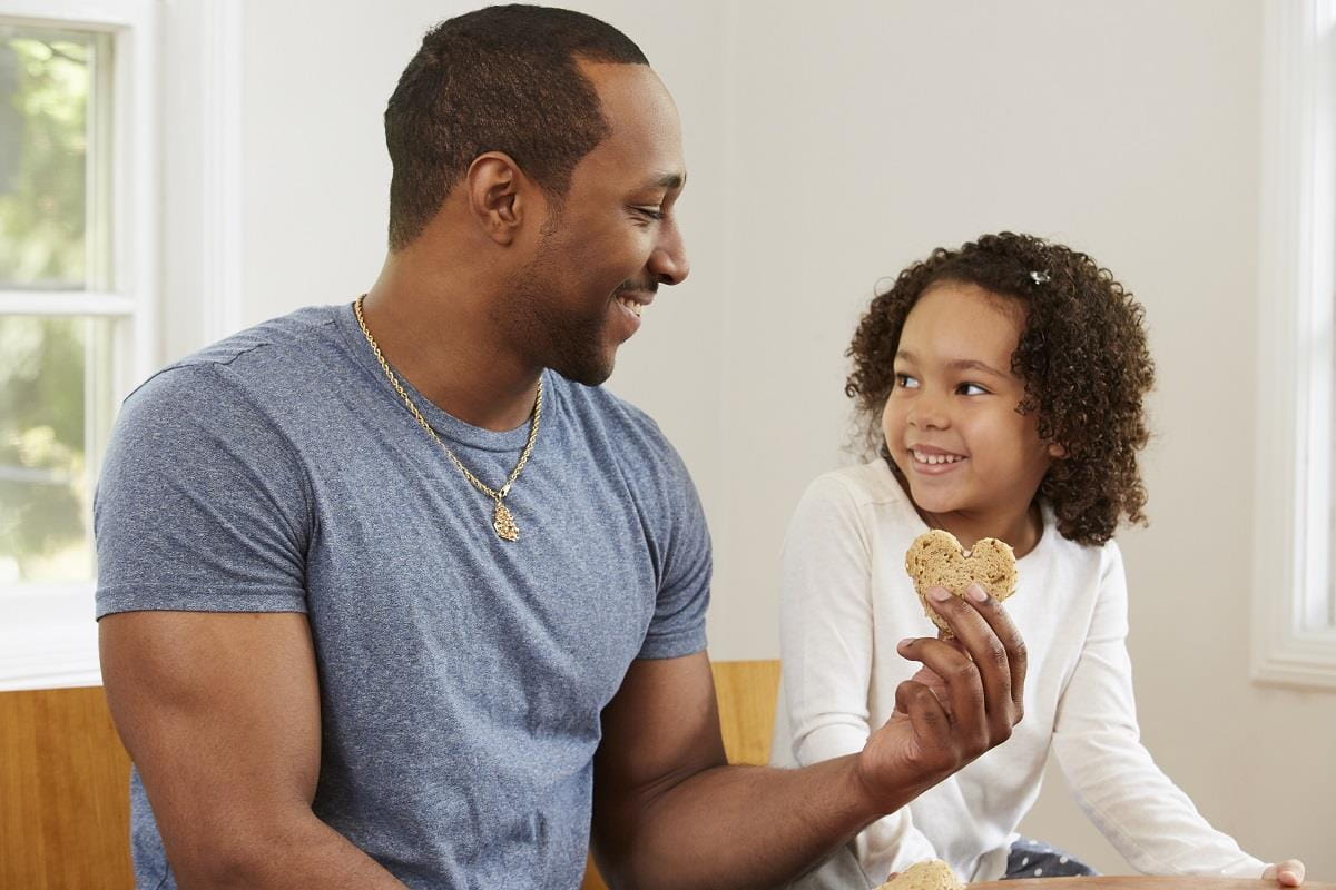 Father giving daughter heart-shaped cookie
