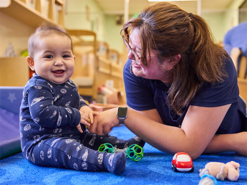 KinderCare teacher with infant in classroom