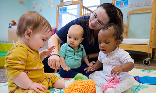 teacher playing with three infants